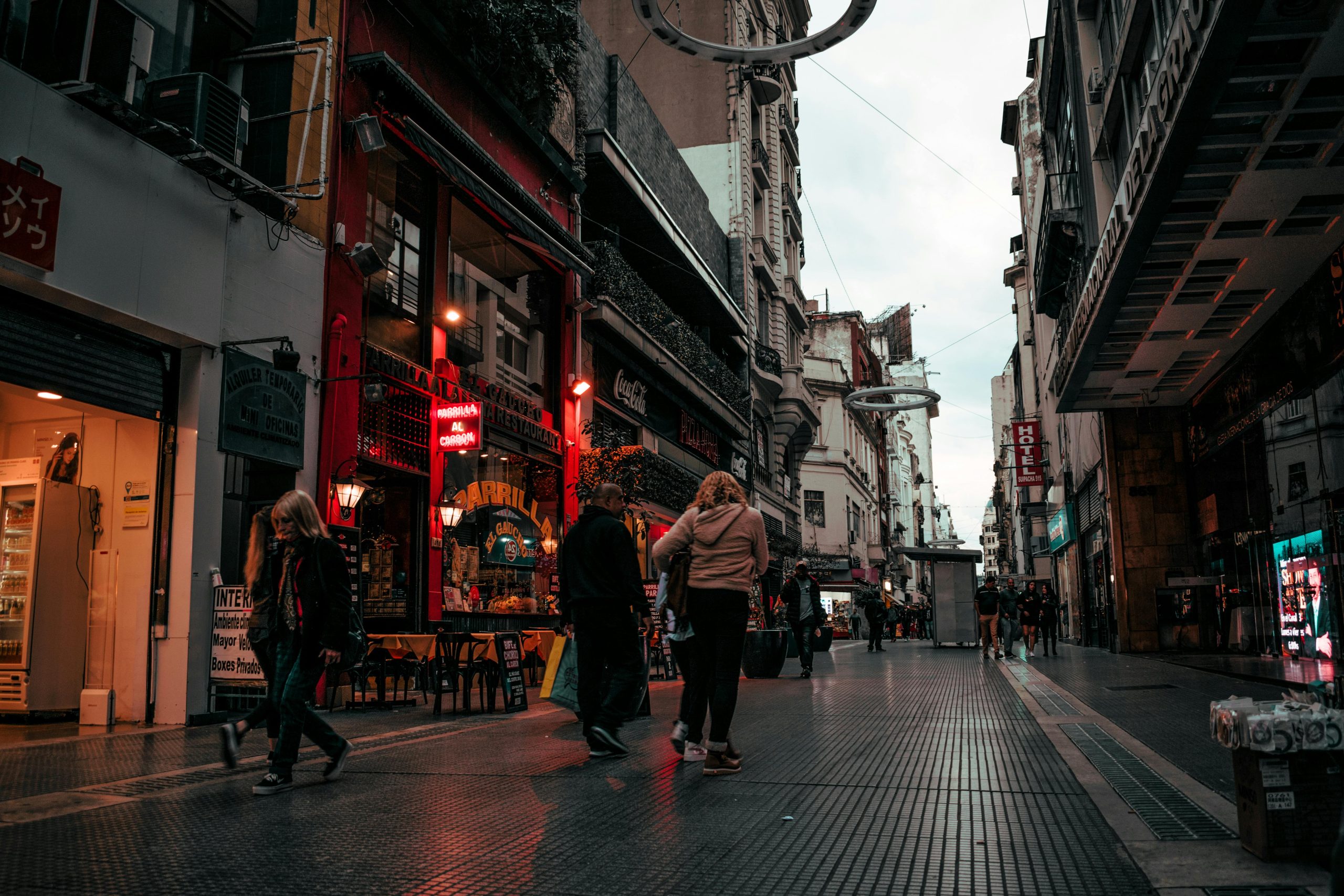 Street view of people walking in a vibrant Buenos Aires alley at dusk.